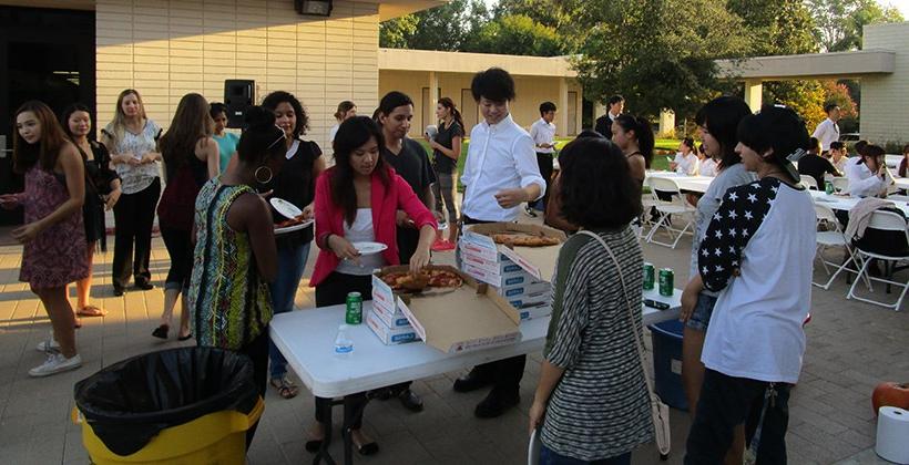Truesdail students and Japanese student visitors eat pizza